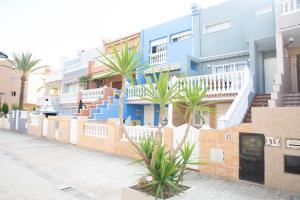 uma fila de casas com escadas azuis e palmeiras em Summer Beach House. em La Pobla de Farnals