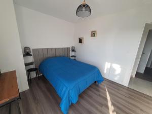 een slaapkamer met een bed met een blauwe deken bij LA PETITE SALAMANDRE des Conches in Longeville-sur-Mer