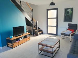een woonkamer met een tv, een bank en een tafel bij LA PETITE SALAMANDRE des Conches in Longeville-sur-Mer