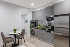 a kitchen with gray cabinets and a table and chairs at Meriton Suites Sussex Street, Sydney in Sydney