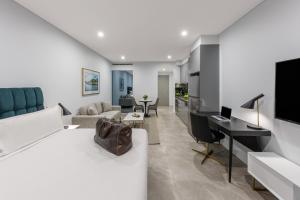 a bedroom with a bed and a desk and a living room at Meriton Suites Sussex Street, Sydney in Sydney