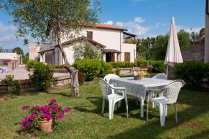 una mesa, sillas y una sombrilla en un patio en Borgo Valmarina, en Follonica