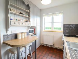 a small kitchen with a wooden table and a sink at Craiglwyd Bach in Llandrillo-yn-Rhôs