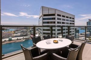 a dining room with a balcony overlooking the ocean at Meriton Suites Sussex Street, Sydney in Sydney