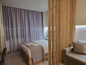 niewielka sypialnia z łóżkiem i krzesłem w obiekcie Iris City Center Premium Studio w Salonikach