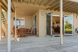 a patio with a table and chairs on a deck at Lakeside Vistas Magic - Rainbow Point Home in Taupo
