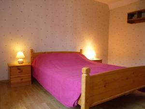 a bedroom with a wooden bed with a purple bedspread at Maison ancienne entièrement rénovée pour 5 personnes in Bény-sur-Mer