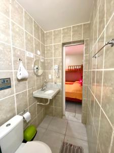 Un baño con inodoro, lavabo y cama. en Pousada Mucuripe, en Fortaleza