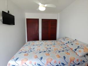 um quarto com uma cama com um edredão floral em Ótimo apartamento na Prainha Torres/RS em Torres