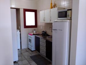 uma cozinha com uma geladeira branca e uma pia em Ótimo apartamento na Prainha Torres/RS em Torres