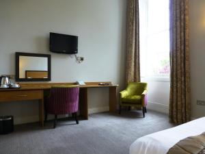 a hotel room with a desk and a mirror at The Riverside House Hotel in Mildenhall