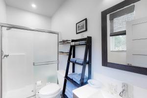 ein Badezimmer mit einem WC, einem Waschbecken und einem Spiegel in der Unterkunft Driftwood Duet in Bandon
