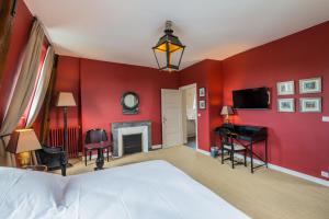 - une chambre avec des murs rouges, un lit et une télévision dans l'établissement La Dixmeresse, à Restigné