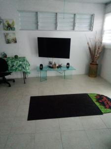 ein Wohnzimmer mit einem Flachbild-TV und einem Tisch in der Unterkunft El Yunque White House in Rio Grande