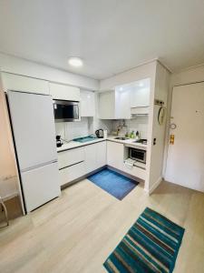uma cozinha com armários brancos e um tapete azul em Departamento mall costanera em Santiago