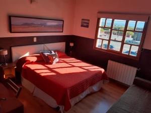 um quarto vermelho com uma cama com um cobertor vermelho em Las Avutardas Hosteria em El Calafate