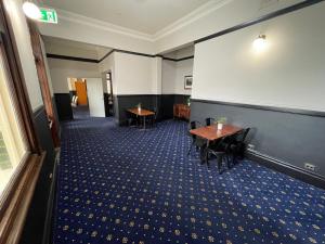 Cette chambre comprend une table, des chaises et un mur. dans l'établissement Royal Hotel Motel Scone, à Scone