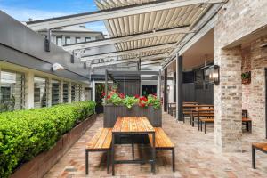 un patio con mesa, bancos y plantas en Grand Hotel and Studios, en Wyong