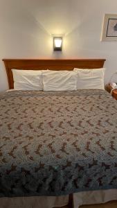 Cama en habitación de hotel con colcha marrón en Highlander Motel en Williams
