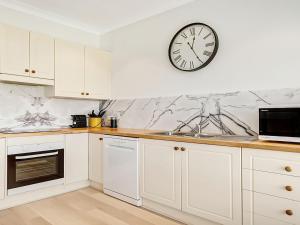 a kitchen with white cabinets and a clock on the wall at Windspray in Culburra Beach