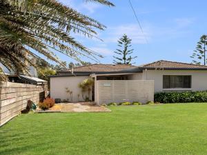 a house with a green lawn in front of it at Windspray in Culburra Beach