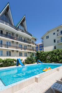 a swimming pool in front of a building at Ev Roshel Hotel in Adler