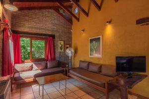 uma sala de estar com um sofá e uma televisão em Cabañas Villa Buriasco em Villa General Belgrano