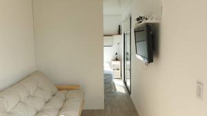 Casa Container Chacra 202 في تانديل: غرفة معيشة مع أريكة بيضاء وتلفزيون بشاشة مسطحة