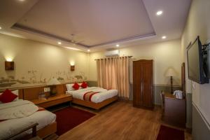 Habitación de hotel con 2 camas y TV en Jungle Safari Resort, en Sauraha