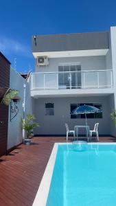 a house with a swimming pool and a patio with an umbrella at Makaha Exclusive Suítes in Praia do Rosa