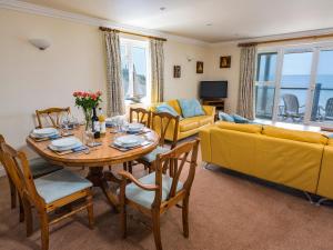 een woonkamer met een tafel en een gele bank bij 3 Thurlestone Rock in Kingsbridge