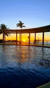 uma piscina com um pôr do sol ao fundo em GOLDEN LAKE, lugar para relaxar em Arraial do Cabo