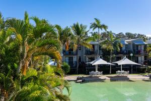 een resort met een zwembad en palmbomen en parasols bij Noosa Lakes Resort in Noosaville
