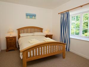 a bedroom with a wooden bed with two towels on it at 3 Moult Farm Cottage in Salcombe