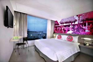 a bedroom with a large bed with a pink wall at favehotel Cimanuk Garut in Garut