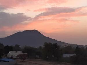 een berg in de verte met een zonsondergang bij Sukha's Place in Pushkar