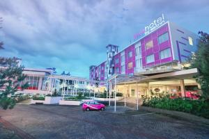 a pink car parked in front of a building at favehotel Cimanuk Garut in Garut