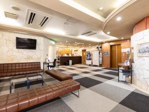 a lobby with couches and a tv on a wall at Hotel Wing International Shimonoseki in Shimonoseki