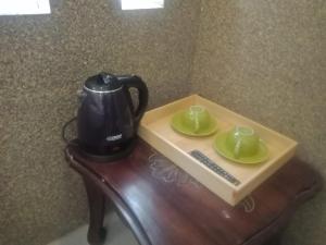 a tea pot and two cups on a table at CALDERA PARK HOMESTAY Syariah in Probolinggo