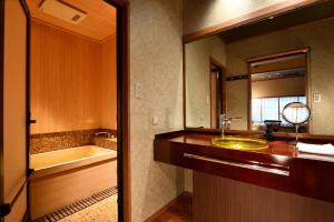 een badkamer met een wastafel, een bad en een spiegel bij Muromachi Yutone Kyokoyado in Kyoto