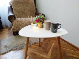 Una mesa blanca con dos tazas y flores. en Comfortable modern apartment en Leópolis