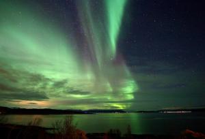 an aurora in the sky over a body of water at Lyngen Alps Panorama in Russelv