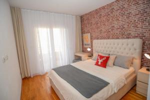 sypialnia z dużym łóżkiem z ceglaną ścianą w obiekcie Lovely Apartment at CITY QUART w mieście Podgorica