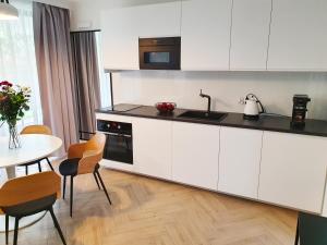 eine Küche mit weißen Schränken und einem Tisch mit Stühlen in der Unterkunft RelaxApart - Komfortowy apartament Kalinowa in Szczyrk