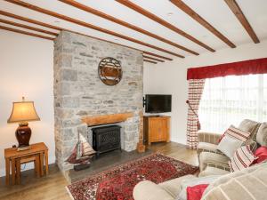 a living room with a stone fireplace and a couch at Tyn Towyn - Ty Glas Golau in Trearddur