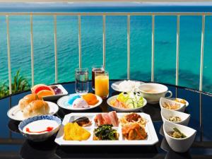 a table topped with plates of food on a balcony at Hotel Resonex Nago in Nago