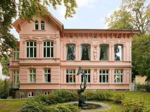 uma casa cor-de-rosa com uma estátua em frente. em Villa Doctores App 02 nur Erwachse em Heringsdorf