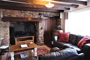 a living room with a leather couch and a stone fireplace at Mariners, Fisherman's Cottage in the Heart of the Harbour with Wonderful Sea Views & Free Dedicated Parking in Brixham