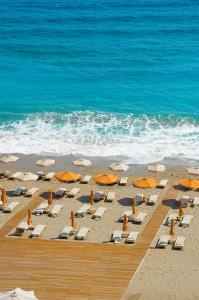 a beach with chairs and umbrellas and the ocean at Konstantinos Palace in Karpathos