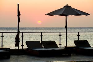 two chairs and an umbrella on the beach with the ocean at Konstantinos Palace in Karpathos